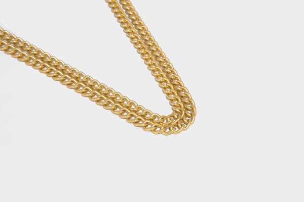 Structured rectangular crossbody bag with glossy finish, three vertical gold-tone embossed plaques, and gold chain strap