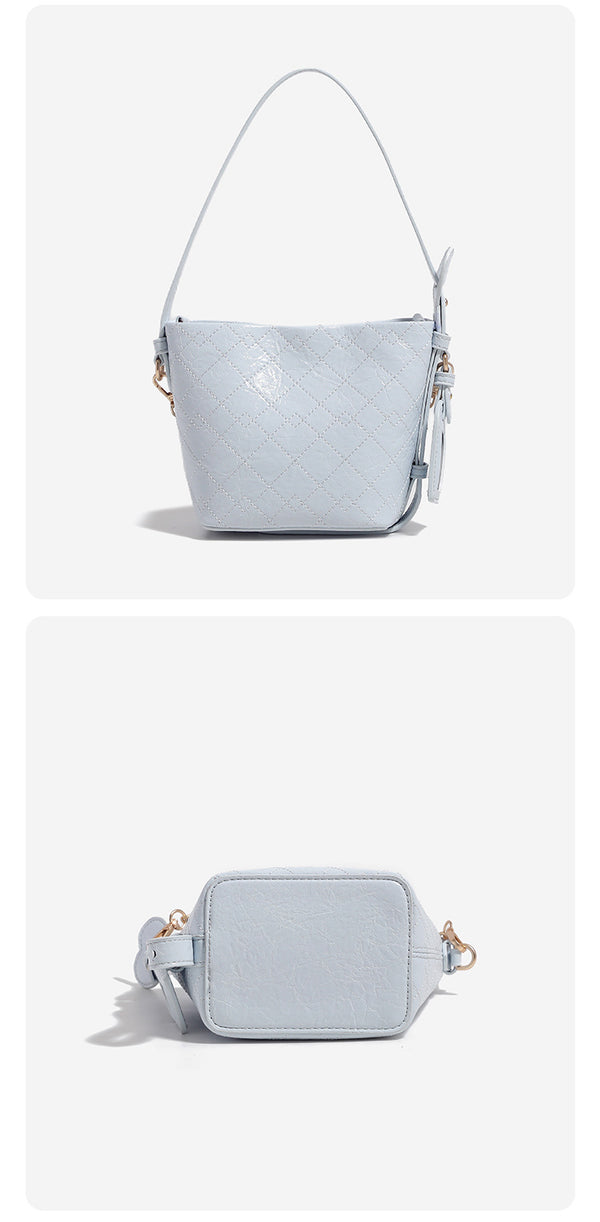 Small diamond-quilted bucket bag with gold-tone chain accent, heart strap detail, hanging tag, and matching zip coin pouch