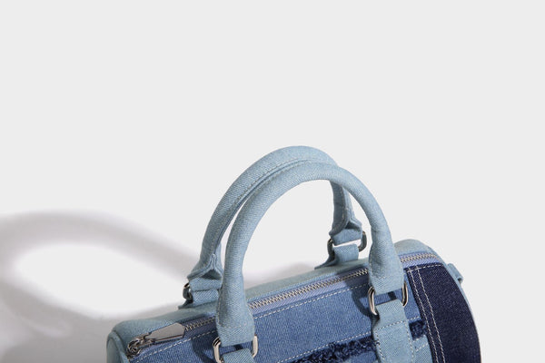 Mini barrel handbag in light and dark denim patchwork with frayed seam trim, dual top handles, top zip closure, and, detail