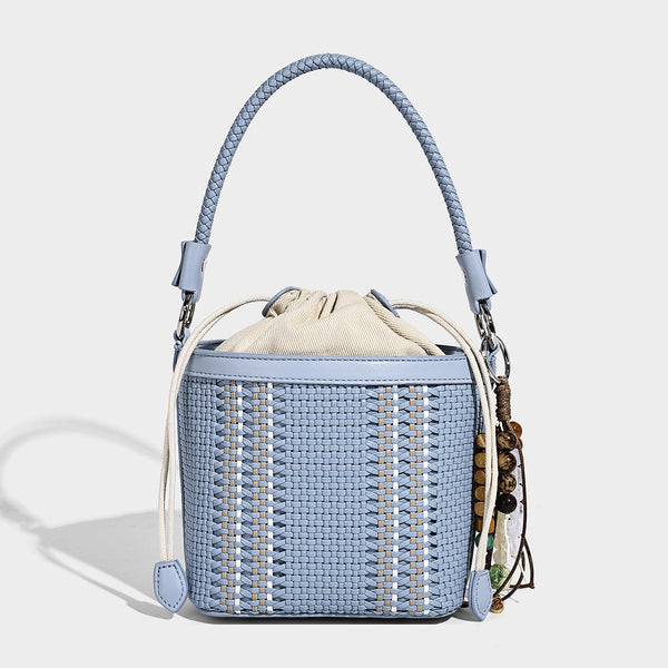 Small woven bucket bag with drawstring top, braided handle, detachable crossbody strap, and silver-tone ring hardware, detail