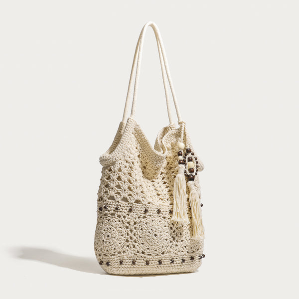 Cream openwork floral crochet tote bag with tassel and wooden bead charm and long rope shoulder straps, detail view 2