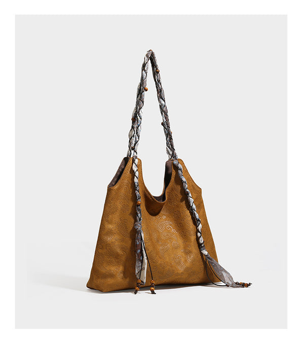 Slouchy paisley-embossed suede-look shoulder tote bag with braided patterned fabric straps and wood bead accents, detail view