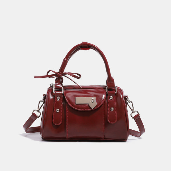 Kleine strukturierte Henkeltasche mit glänzender Oberfläche, zwei Tragegriffen, aufgesetzter Fronttasche, herzförmigem Verschlussanhänger und silberfarbenem