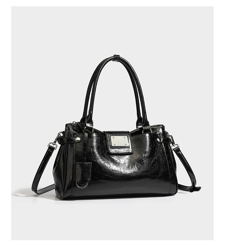 Structured glossy crinkled leather-look satchel with double top handles, front metal-plaque tab, silver-tone hardware, and