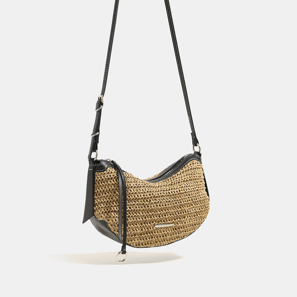 Compact crescent-shaped woven straw crossbody bag with black leather-look trim, top zip closure, and adjustable shoulder
