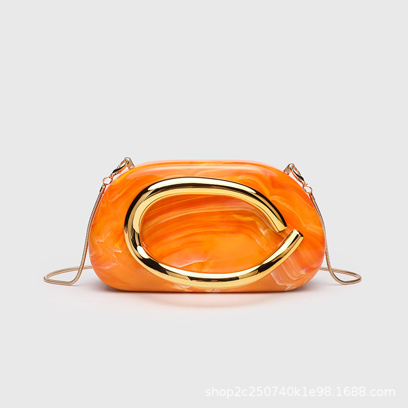 Kleine rechteckige Crossbody-Clutch mit abgerundeten Ecken, oversized poliertem C-förmigem Goldgriff und schmalem Goldkettenriemen, Detailansicht