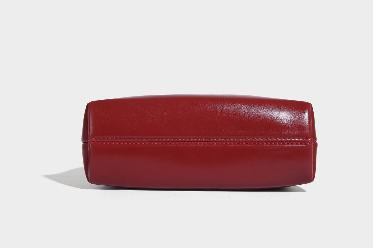 Kleine kuppelförmige Henkeltasche in glänzender Lederoptik mit Kordelzugverschluss, weißem Spitzen-Schleifenanhänger und silberfarbenen Metallbeschlägen