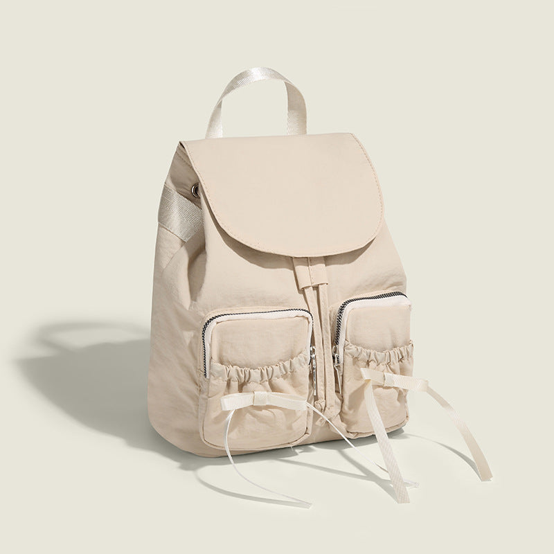 Soft matte nylon drawstring backpack with ruched bow-detail front zip pockets, top carry handle, and silver-tone hardware