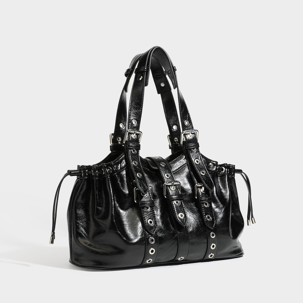Large black glossy leather-look tote bag with silver buckle straps, eyelet grommet panels, drawstring side gathers, and
