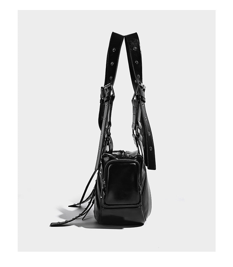 Glossy black crescent shoulder bag with silver-tone rivets, multiple zip pockets, and long adjustable studded straps, detail
