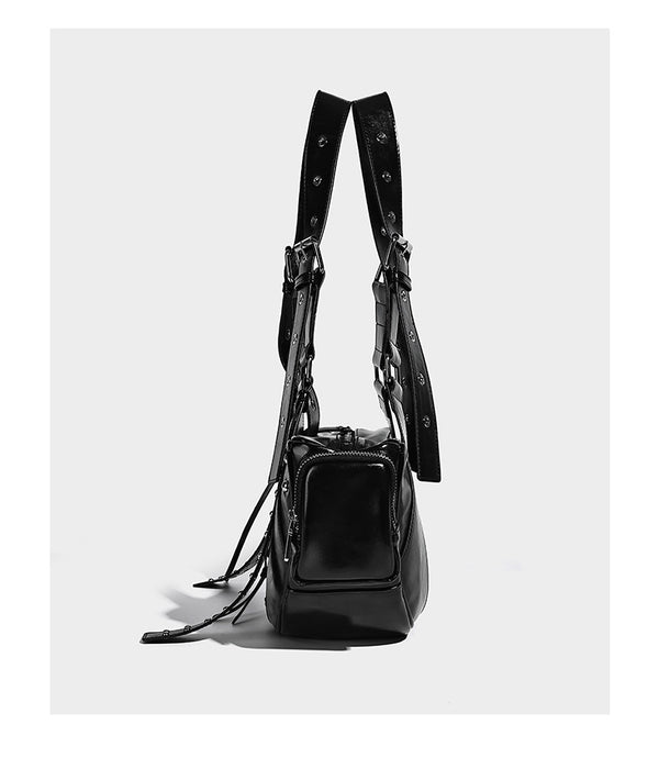 Glossy black crescent shoulder bag with silver-tone rivets, multiple zip pockets, and long adjustable studded straps, detail