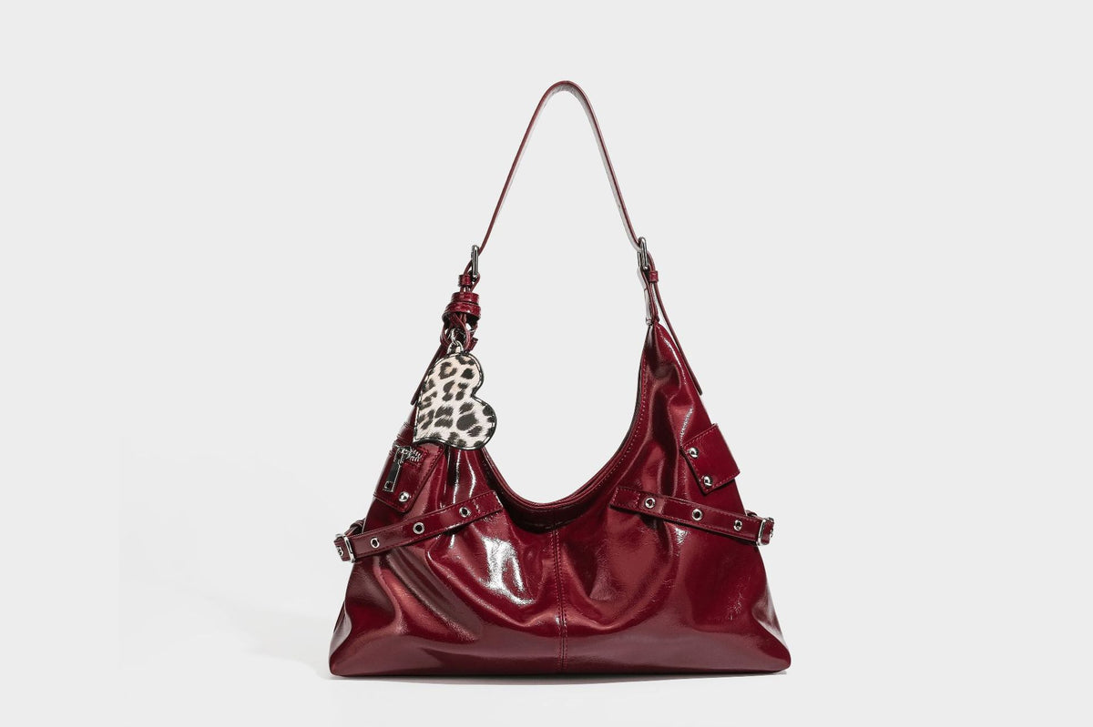 Glänzende dunkelbraune, lässig geschnittene Hobo-Schultertasche mit Riemendetail mit silberfarbenen Ösen, Reißverschlussfach auf der Vorderseite und Herz mit Leopardenmuster