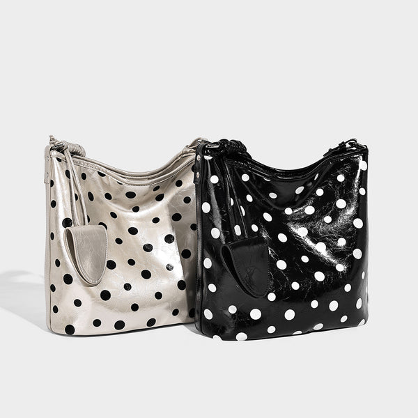 Glänzende schwarze Schultertasche im Bucket-Stil mit weißen Tupfen, langem verstellbarem Riemen und Kordelzugverschluss, Detailansicht 2