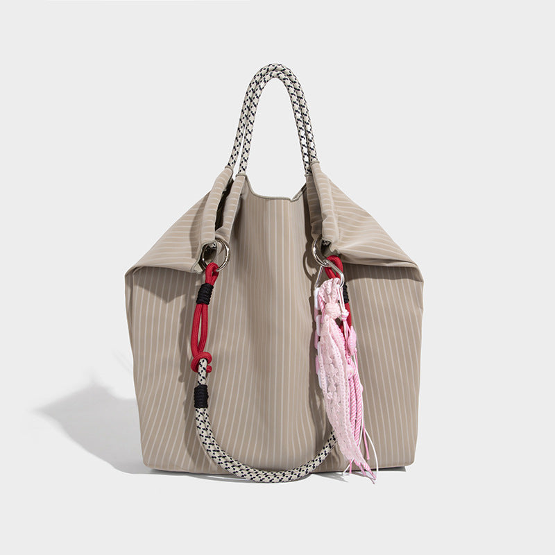 Slouchy pinstripe tote bag with braided rope handles, metal ring hardware, and colorful knotted rope charm, detail view 9