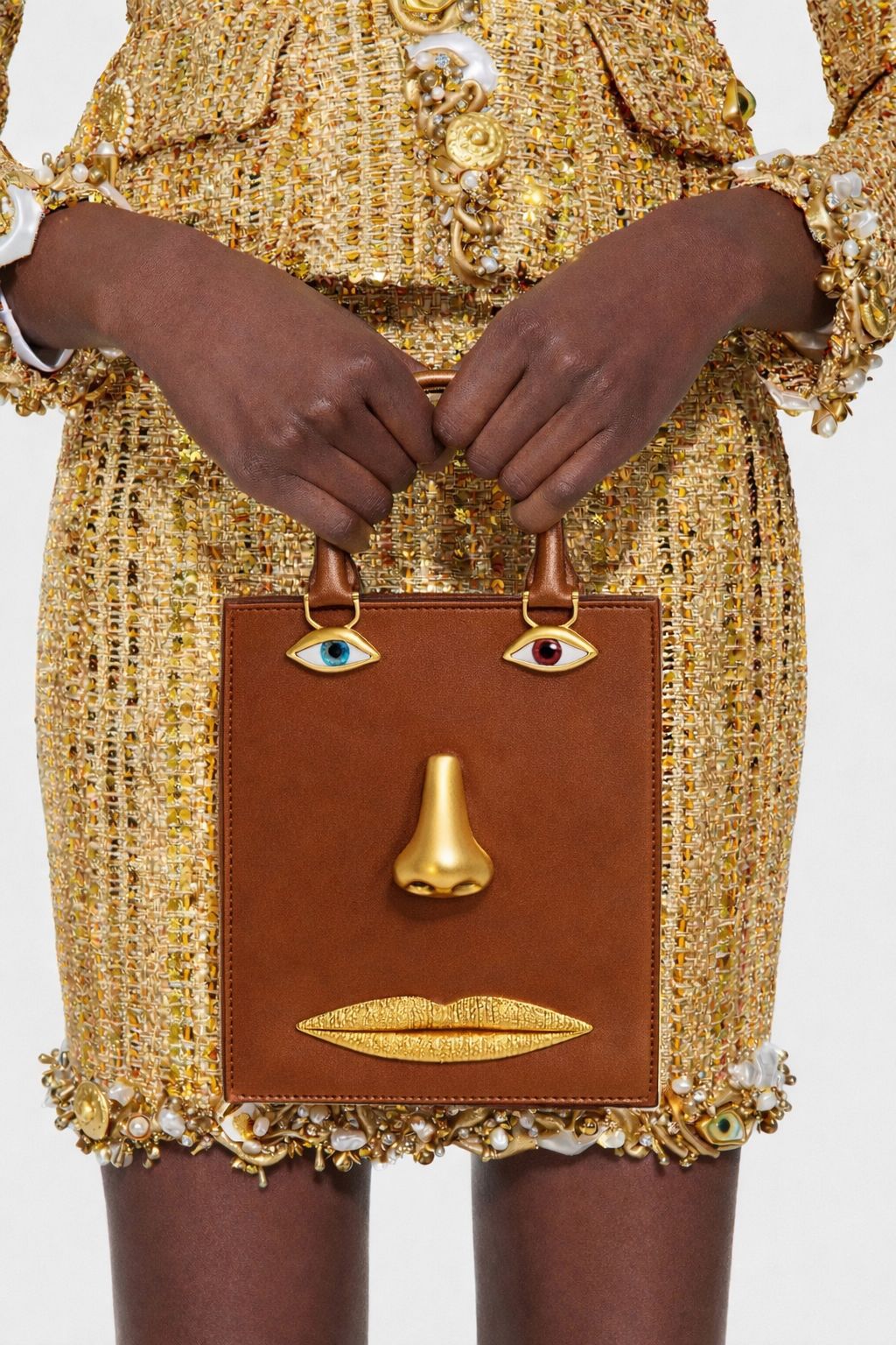 Structured rectangular top-handle bag in tan leather-look finish with gold-tone sculptural face hardware including