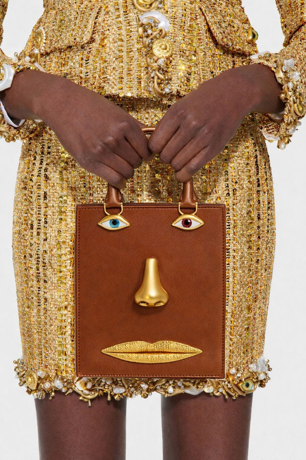 Structured rectangular top-handle bag in tan leather-look finish with gold-tone sculptural face hardware including