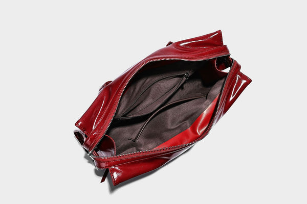Structured rectangular glossy tote shoulder bag with belt buckle front strap and dangling charm hardware, detail view 21