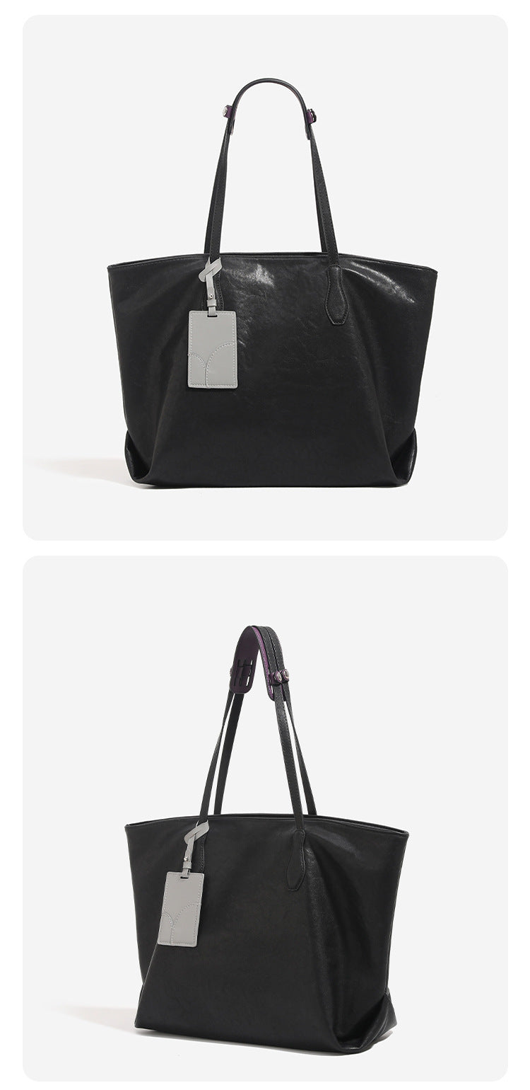 Oversized slouchy leather-look tote bag with long shoulder straps, contrast grey hanging tag, and silver-tone hardware