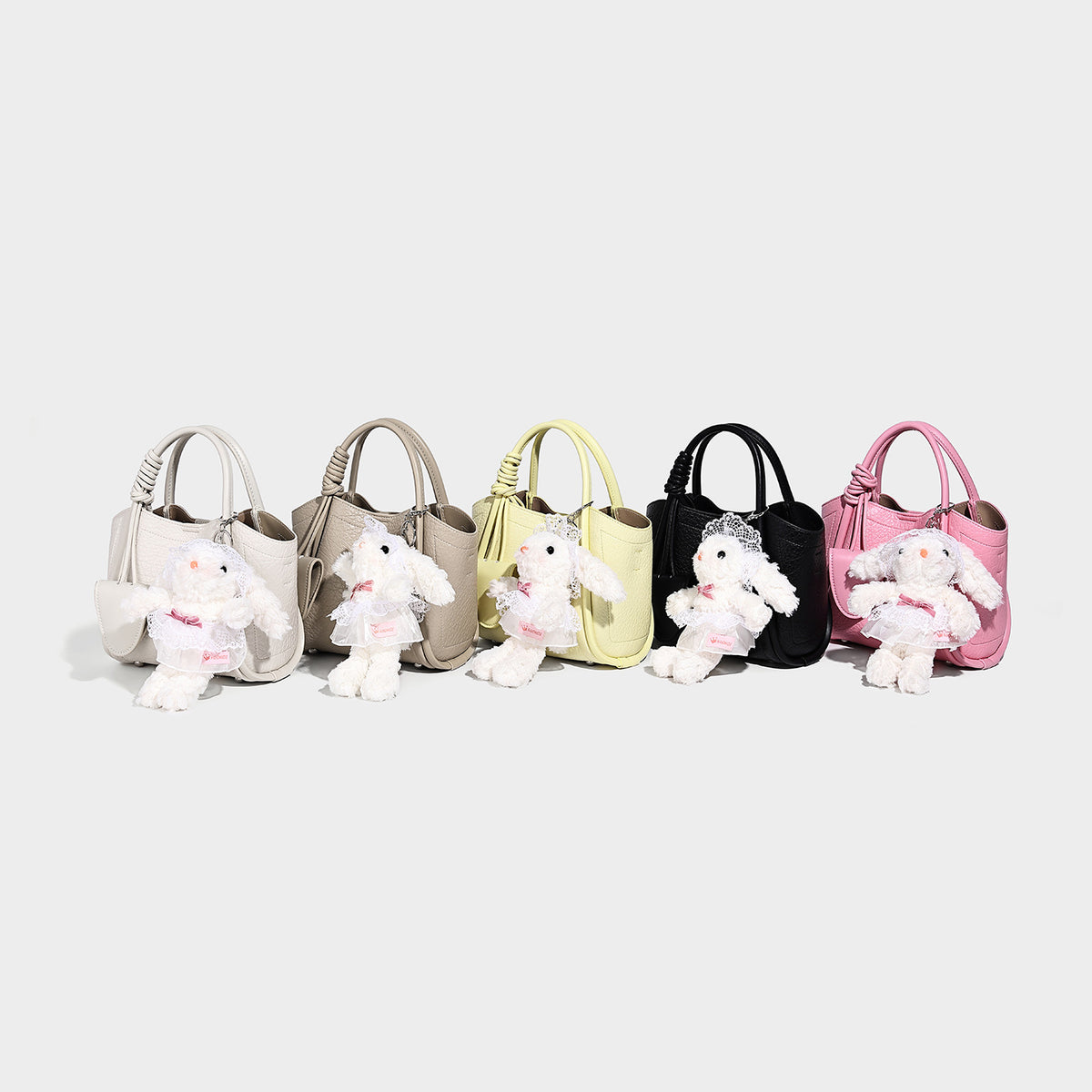 Structured mini tote bag in pebbled leather-look finish with knotted top handles, front flap pocket, and detachable shoulder