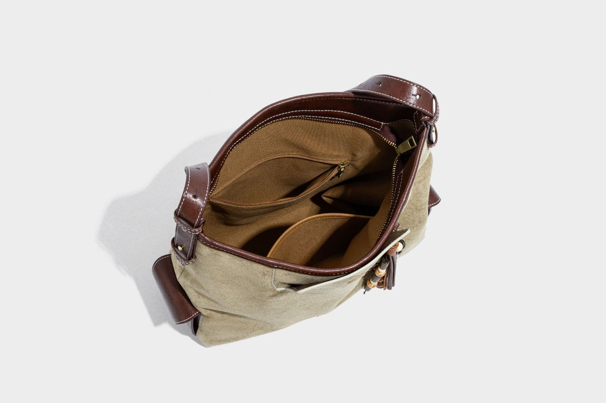 Lässig fallende Hobo-Schultertasche in Khaki aus mattem Material in Wildlederoptik mit dunkelbraunem Besatz in Lederoptik, Quastenanhänger mit Perlen und seitlicher Klappe, Detailansicht