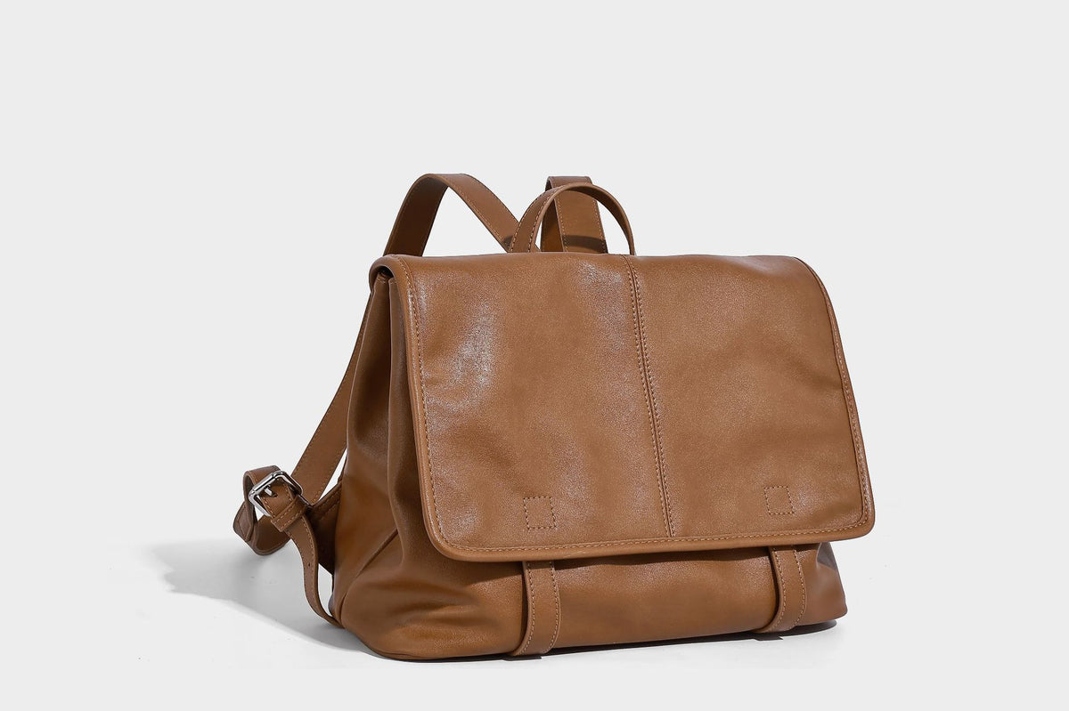 Structured tan leather-look flap backpack handbag with top handle, silver buckle hardware, and fold-over front closure