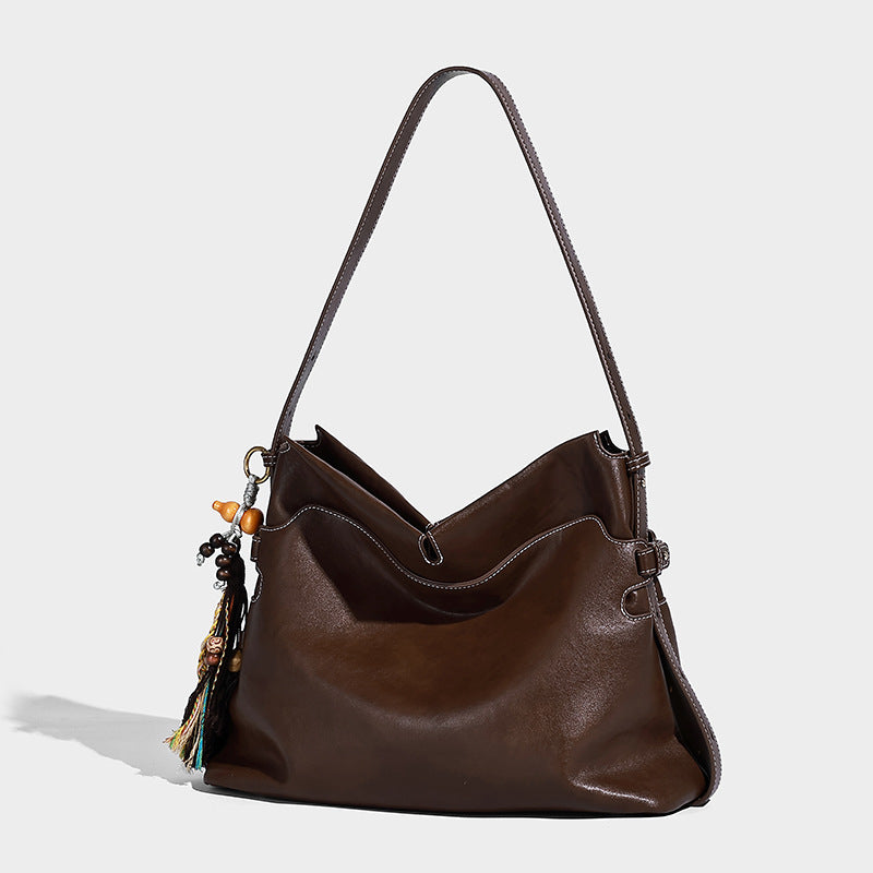 Large slouchy leather-look hobo tote bag with open top, adjustable shoulder strap, and colorful tassel bead charm, front view
