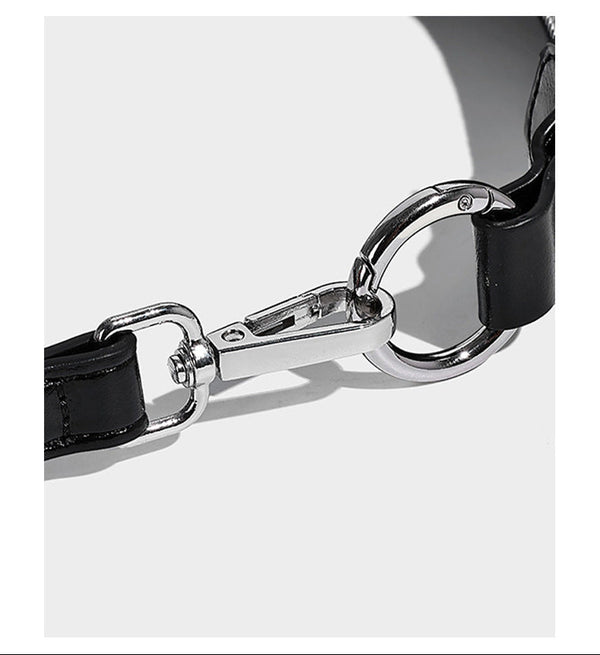 Glossy black slouchy hobo shoulder bag with silver-tone hardware, belt-style grommet strap at base, and long adjustable