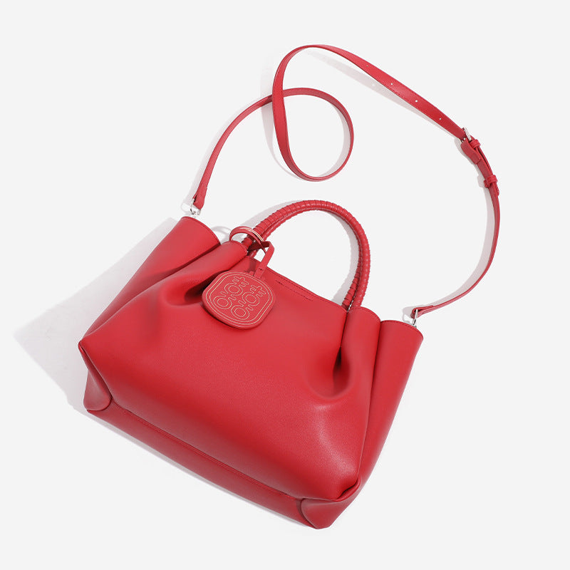 Strukturierte Tote-Bag in mattem Rot mit gedrehten, umwickelten Tragegriffen, Anhänger mit Doppelglück-Symbol und herausnehmbarem grauem Innenfach mit Reißverschluss