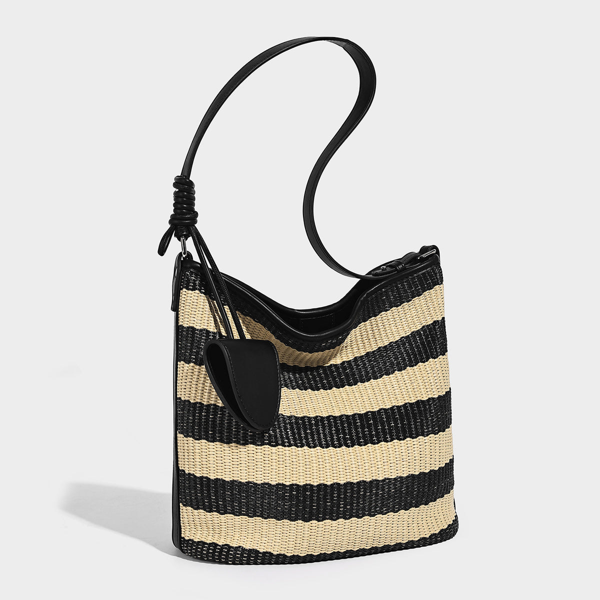 Gestreifte Webstoff-Beuteltasche in Schwarz und Beige mit schwarzem Besatz in Lederoptik, offenem oberen Rand und langem verstellbarem Schulterriemen, Detailansicht