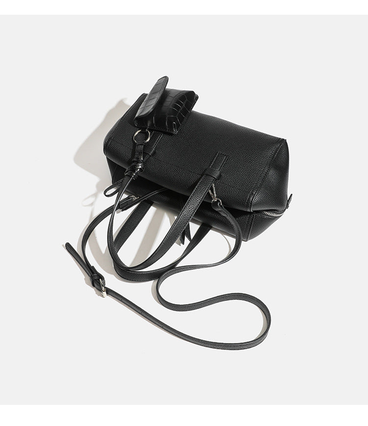 Structured pebbled leather-look top-zip barrel bag with dual handles, detachable shoulder strap, and attached croc-pattern
