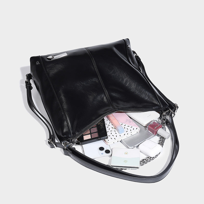 Glänzend schwarze, weich fallende Hobo-Tote-Bag mit silberfarbenem Kettenelement, Reißverschluss oben und langen Schulterriemen, Detailansicht 4