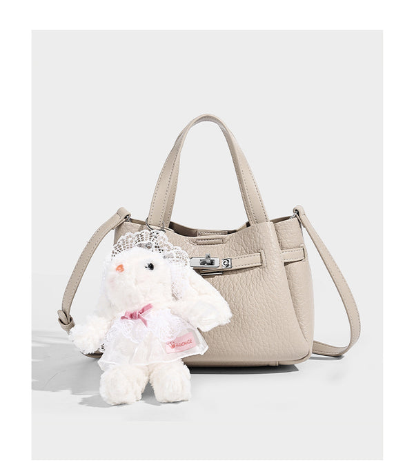 Small structured pebbled bucket tote with double top handles, silver turn-lock hardware, and detachable shoulder strap