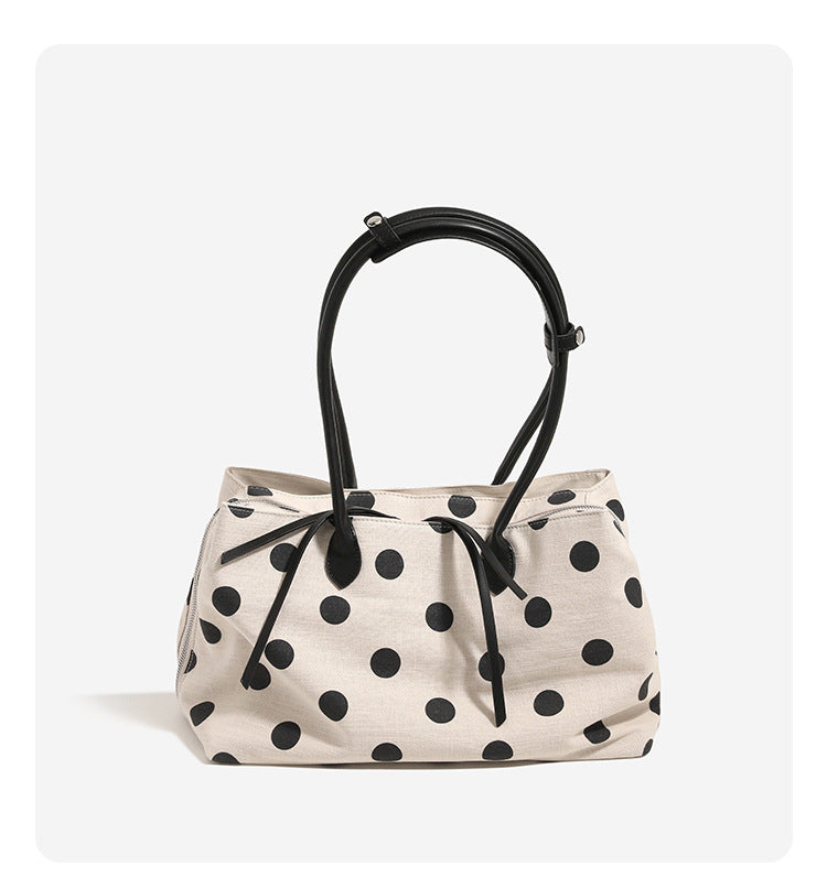 Cream canvas tote bag with black polka dots, rounded leather-look handles, and zip-top closure, detail view 7