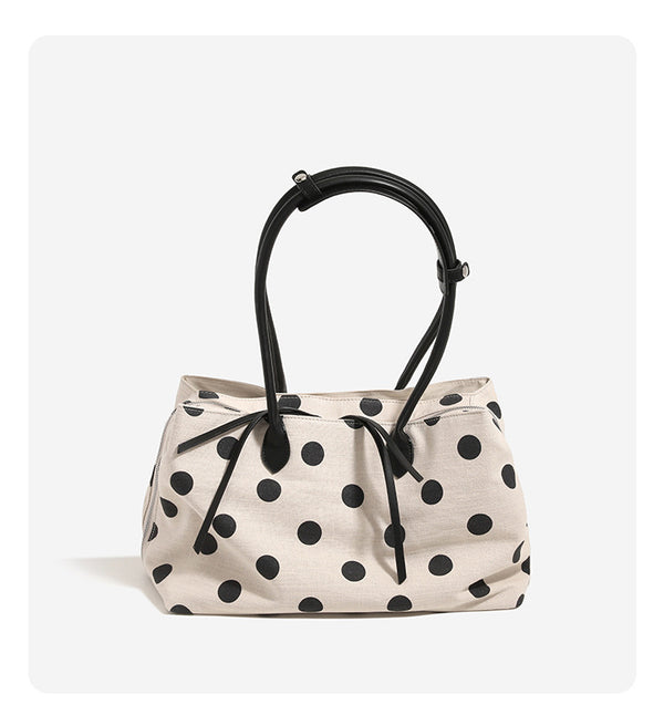 Cream canvas tote bag with black polka dots, rounded leather-look handles, and zip-top closure, detail view 7
