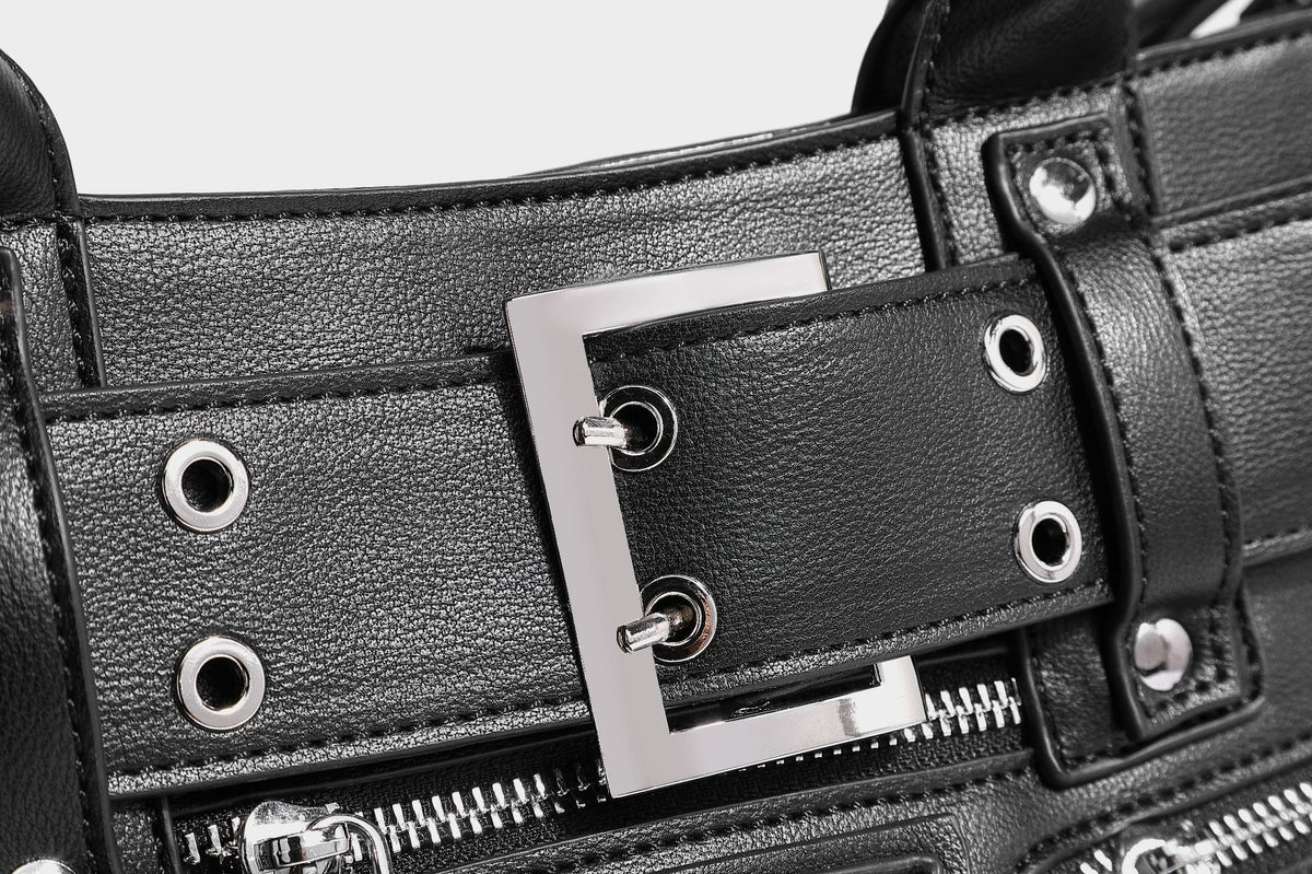Black structured rectangular satchel bag with silver-tone rivets, large front buckle strap, zip pockets, dual top handles