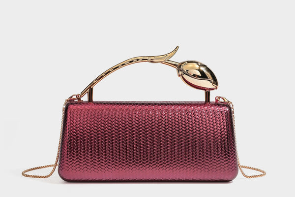Structured rectangular metallic woven clutch bag with sculptural gold-tone leaf top handle and detachable chain strap, detail