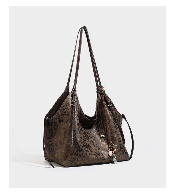 Slouchy leopard-print shoulder tote bag in tan and brown with long double straps, side tie straps, and dangling charm, detail