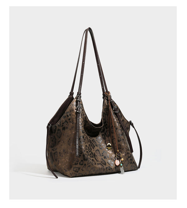 Slouchy leopard-print shoulder tote bag in tan and brown with long double straps, side tie straps, and dangling charm, detail