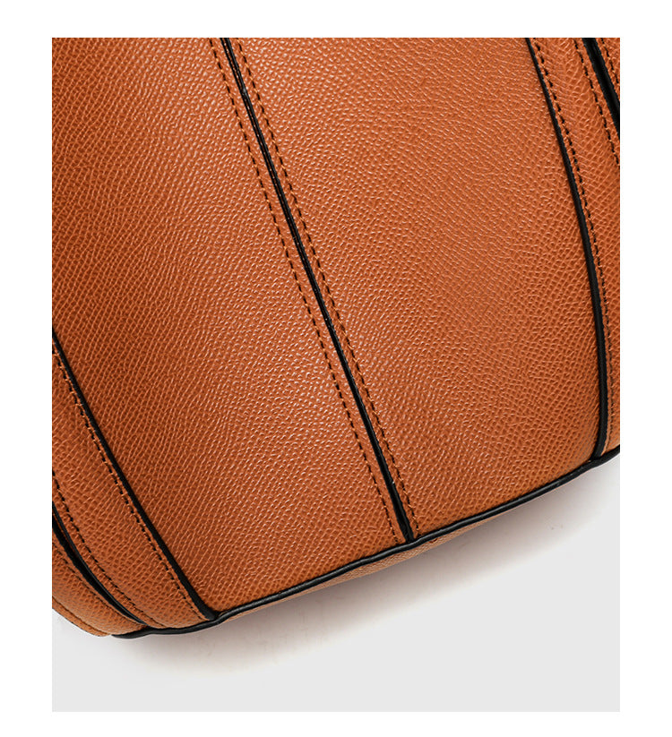 Structured open-top tote bag in tan brown pebbled leather-look finish with vertical seam accents, black edge piping, curved