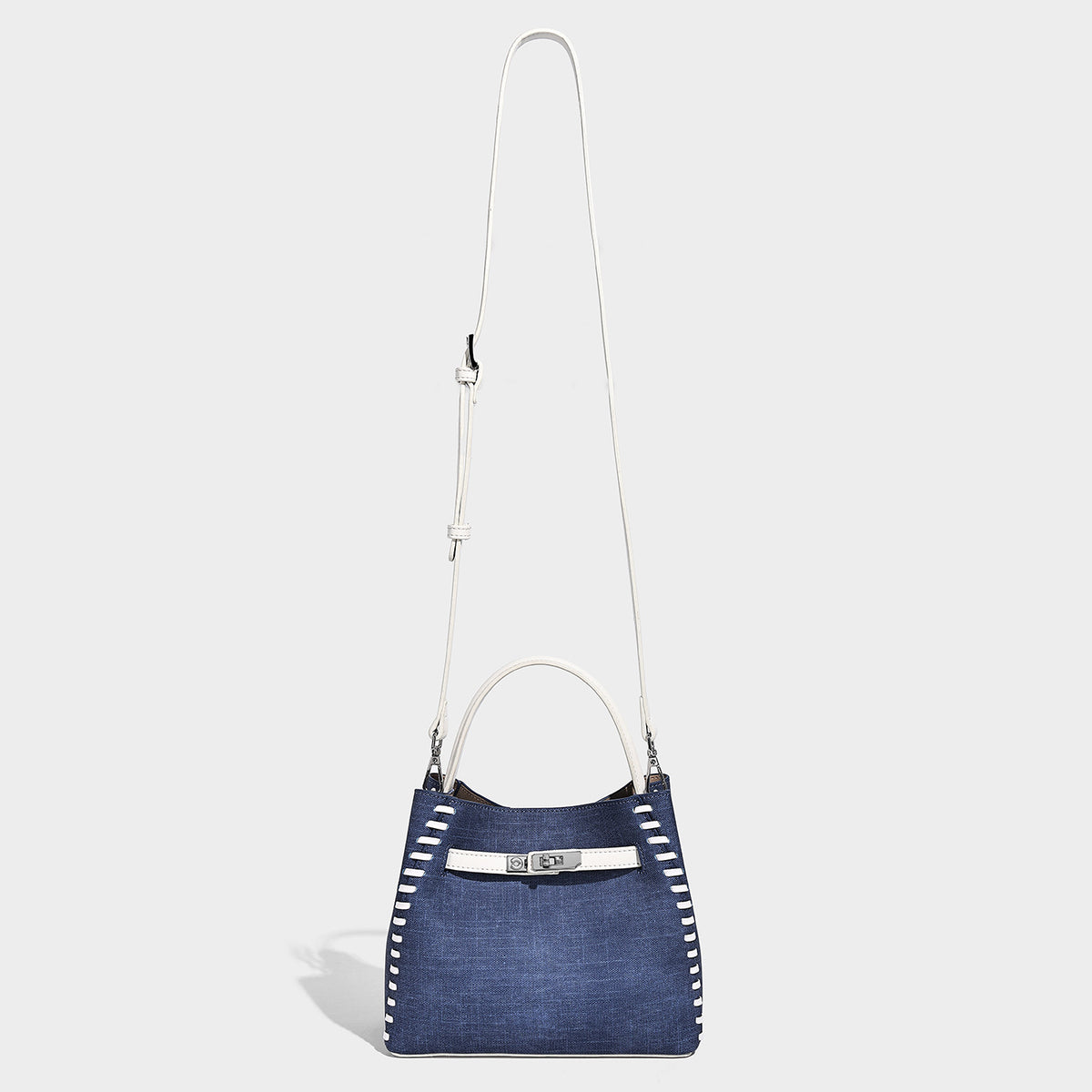 Strukturierte Bucket-Bag aus Denim mit weißem Sattelstich-Besatz, silberfarbenem Drehverschluss, kurzen Henkeln und einem langen, verstellbaren