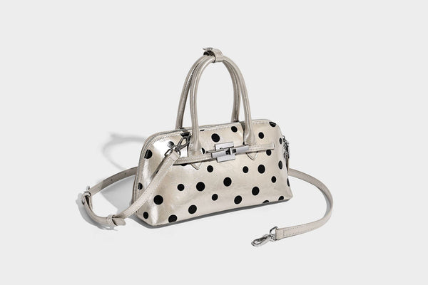 Glossy structured polka-dot satchel bag with dual top handles, silver turn-lock hardware, and detachable shoulder strap