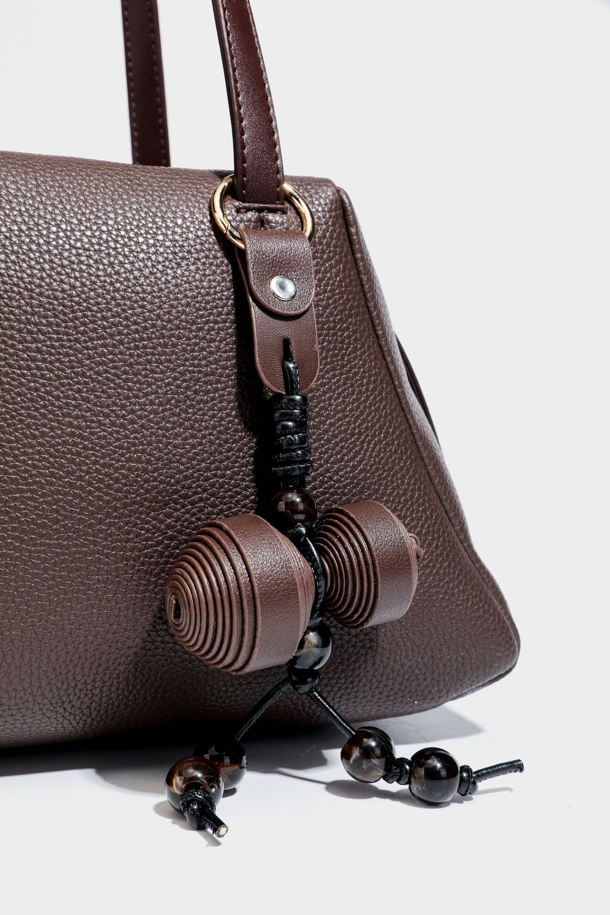 Structured trapezoid shoulder bag in dark brown pebbled leather-look finish with slim double straps, top zip closure, side