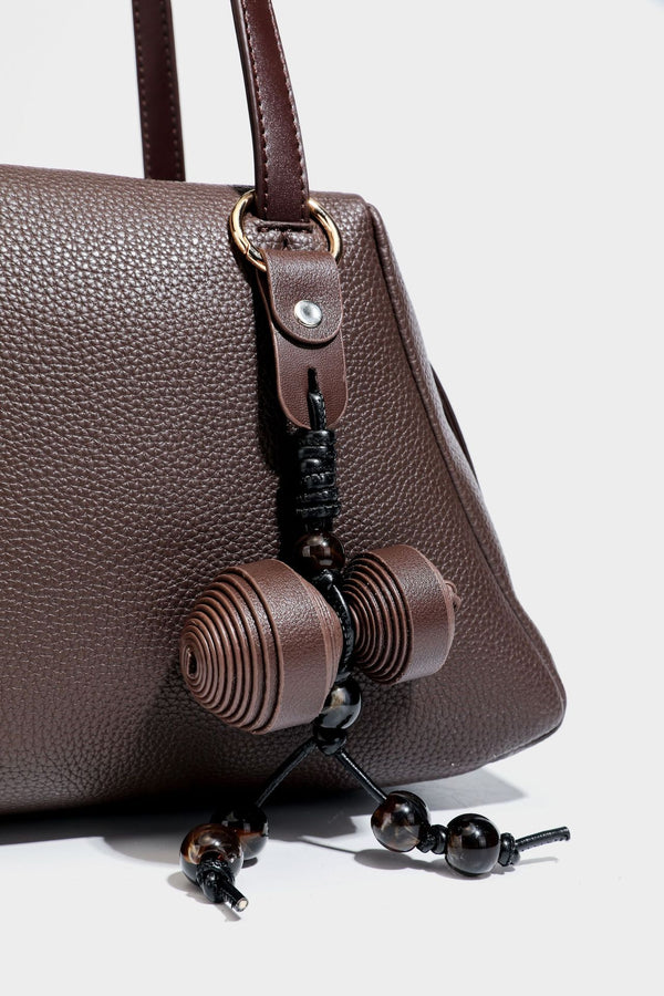 Structured trapezoid shoulder bag in dark brown pebbled leather-look finish with slim double straps, top zip closure, side