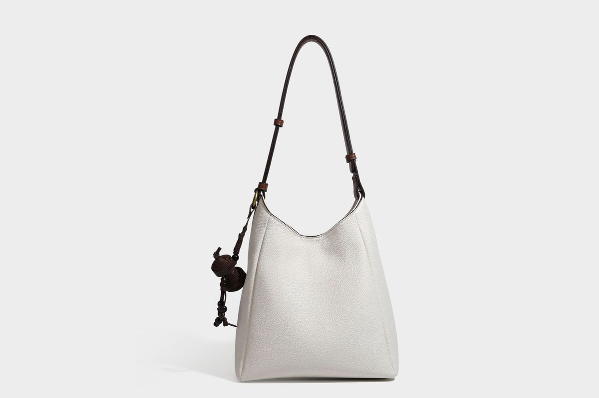 Hobo-Schultertasche in dunklem Espresso mit genarbter Oberfläche, warmen cognacfarbenen Details, verstellbarem schmalem Riemen, goldfarbenen Ringbeschlägen und geknotetem