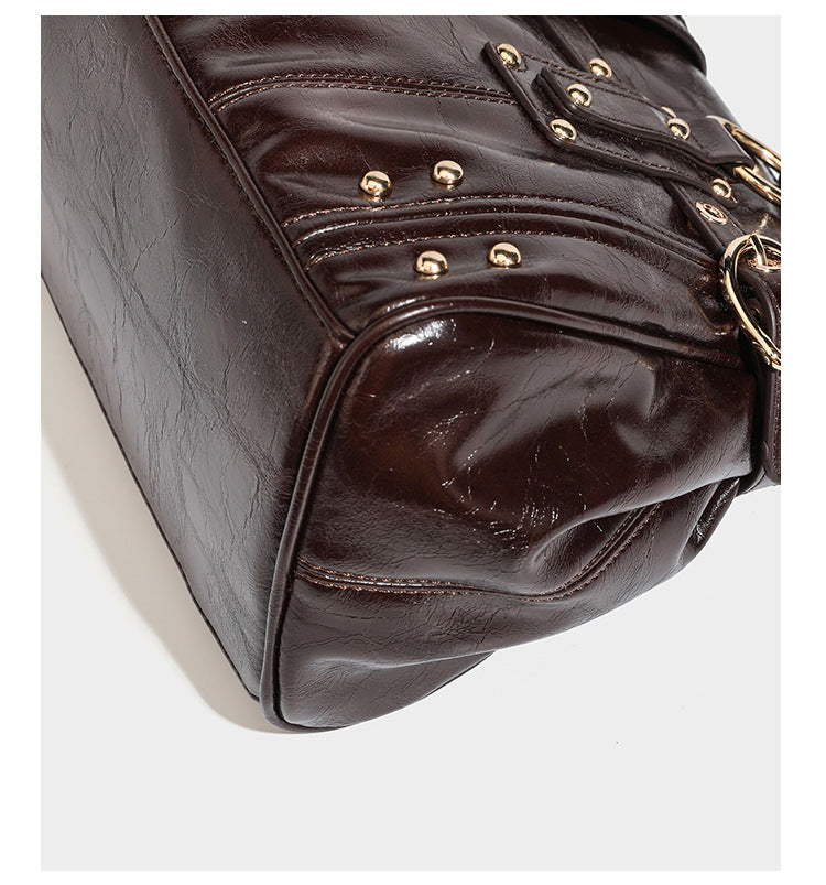 Dark brown glossy leather-look structured satchel tote with gold-tone studs, buckle straps, dual top handles, and detachable