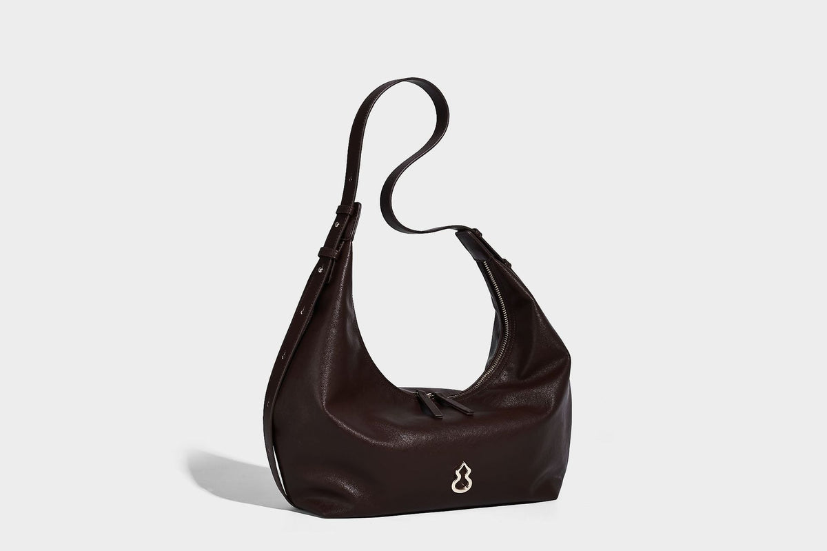 Lässig fallende, sichelförmige Hobo-Schultertasche in glatter dunkelbrauner Lederoptik mit Logo-Anhänger in Goldoptik und verstellbarem Schulterriemen