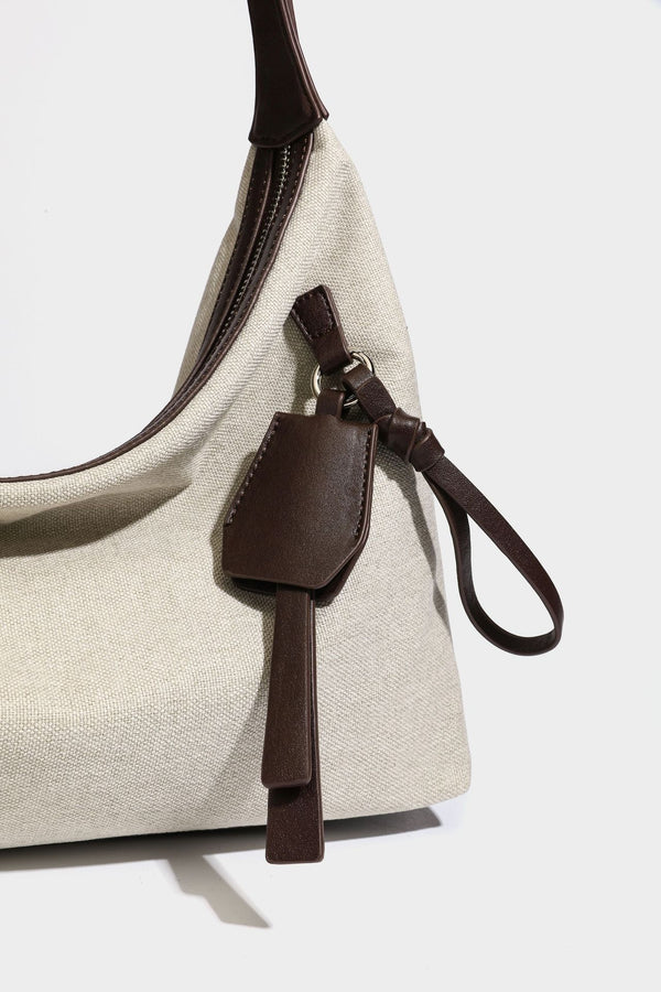 Lässige Hobo-Schultertasche aus haferfarbenem Canvas mit dunkelbraunen Besätzen in Lederoptik, silberfarbenem Reißverschluss und langem, verstellbarem