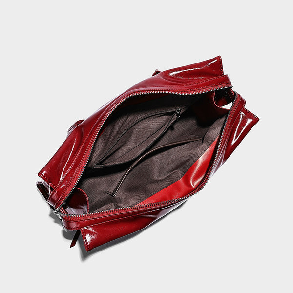 Structured rectangular glossy tote shoulder bag with belt buckle front strap and dangling charm hardware, detail view 4