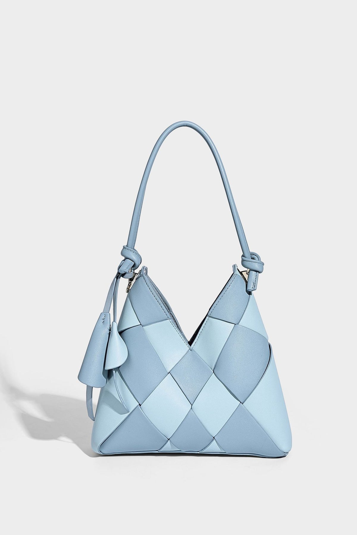 Compact bucket shoulder bag with black-and-white diamond patchwork panels, knotted top handle, gold-tone hardware, and
