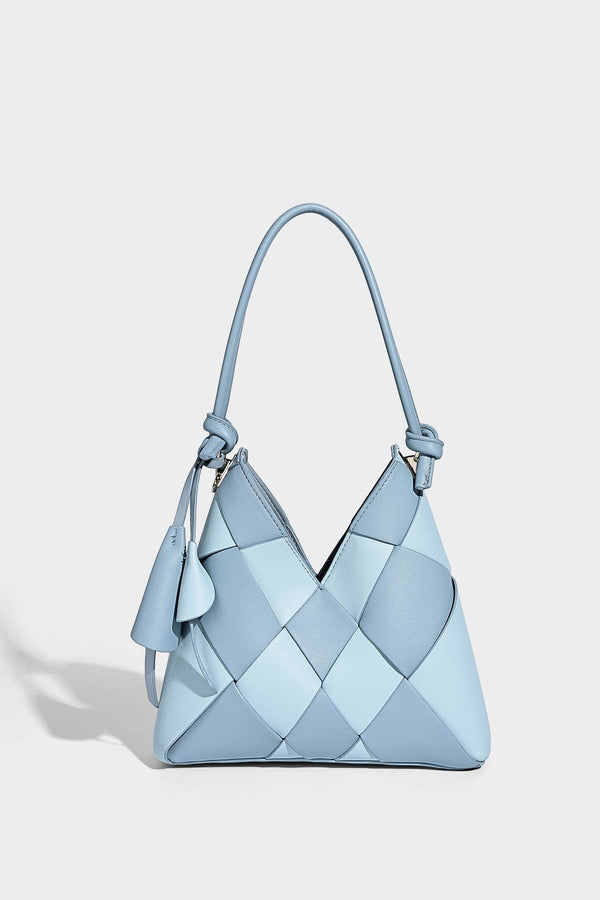 Compact bucket shoulder bag with black-and-white diamond patchwork panels, knotted top handle, gold-tone hardware, and